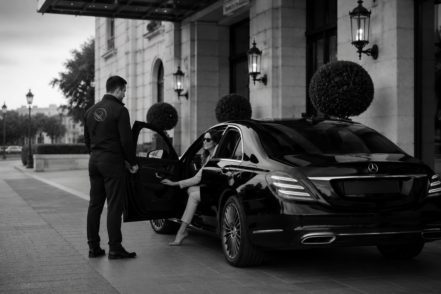 A Romanos valet welcoming a guest and assisting with her arrival